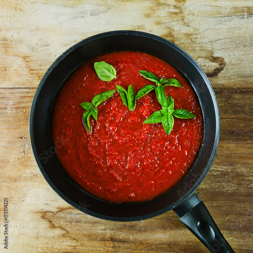 tomato sauce in a pan and fresh basil leaves