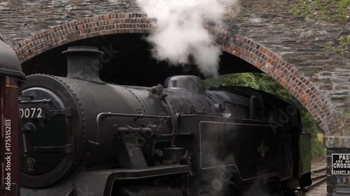 Stationary stem train smoking under a tunnel at Llangollen station, Wales.