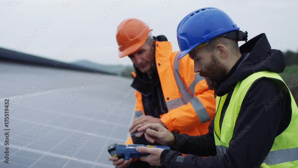 Technicians checking the panels at solar energy installation Technicians checking the panels at solar energy installation
