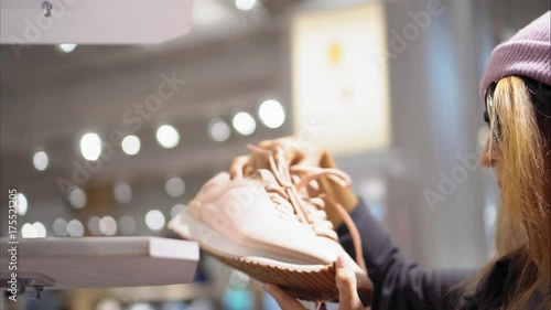 A young hipster female chooses new sneakers in the store. Shopping