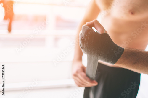 Handsome bearded boxer with bare torso wrapping his hands, ready to fight at the fight club © estradaanton