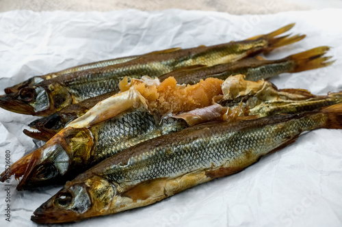 Delicious smoked fish smelt osmerus caviar lying on light-colored paper on a wooden background. photo