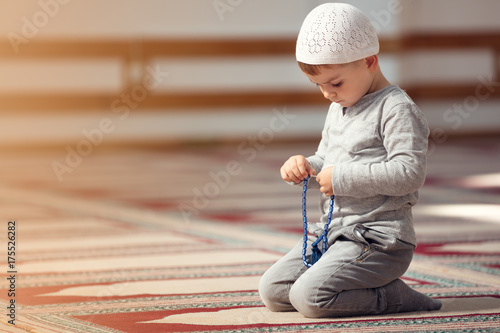 Tela The Muslim child prays in the mosque, the little boy prays to God, Peace and love in the holy month of Ramadan