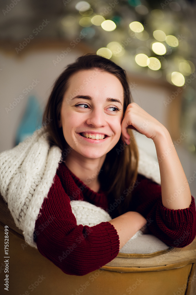 Smiling beautiful woman sitting over Christmas tree on the background Smiling beautiful woman sitting over Christmas tree on the background