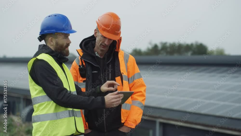 Technicians with computer tablet discussing operations at solar energy plant. Technicians with computer tablet discussing operations at solar energy plant.