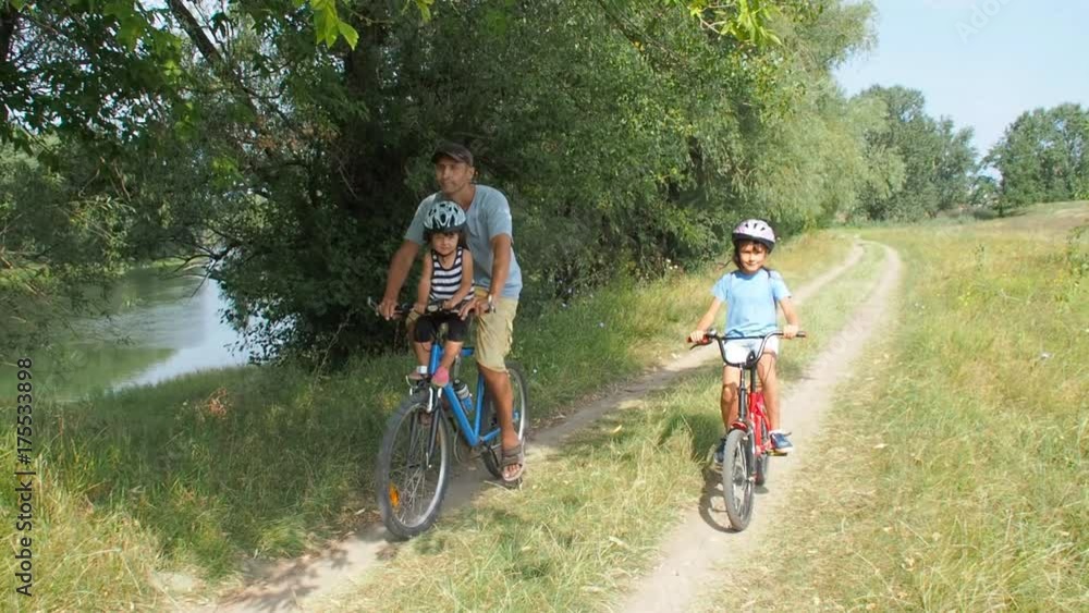 Happy family on bicycles. Father with daughters ride bicycles in nature. Happy family on bicycles. Father with daughters ride bicycles in nature.