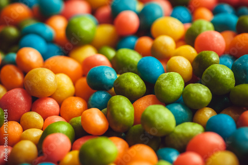 Rainbow colors on background of bright candy small round forms. Abstract sweets with raisins or nuts stuffing