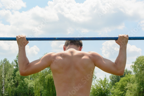 male athlete pulls up on a horizontal bar