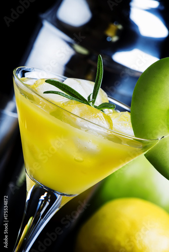 Apple martini cocktail with dry vermouth, syrup, lemon juice, green apple, rosemary and ice cubes, black background, selective focus photo