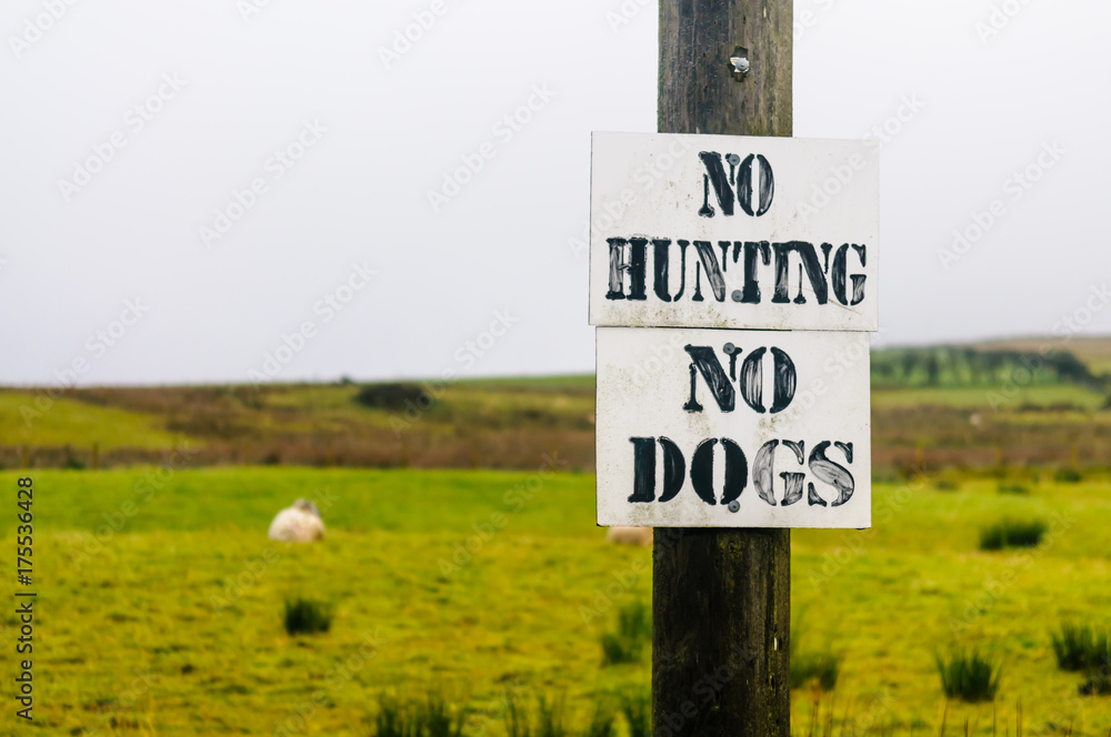 Signs on a fence around a field of sheep saying Signs on a fence around a field of sheep saying