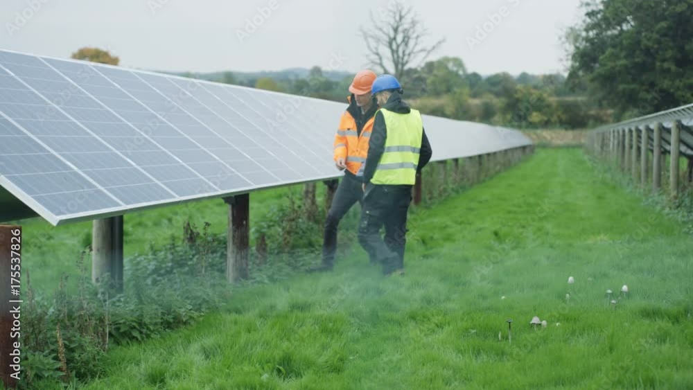 Technicians working at solar energy plant, checking the panels & talking Technicians working at solar energy plant, checking the panels & talking