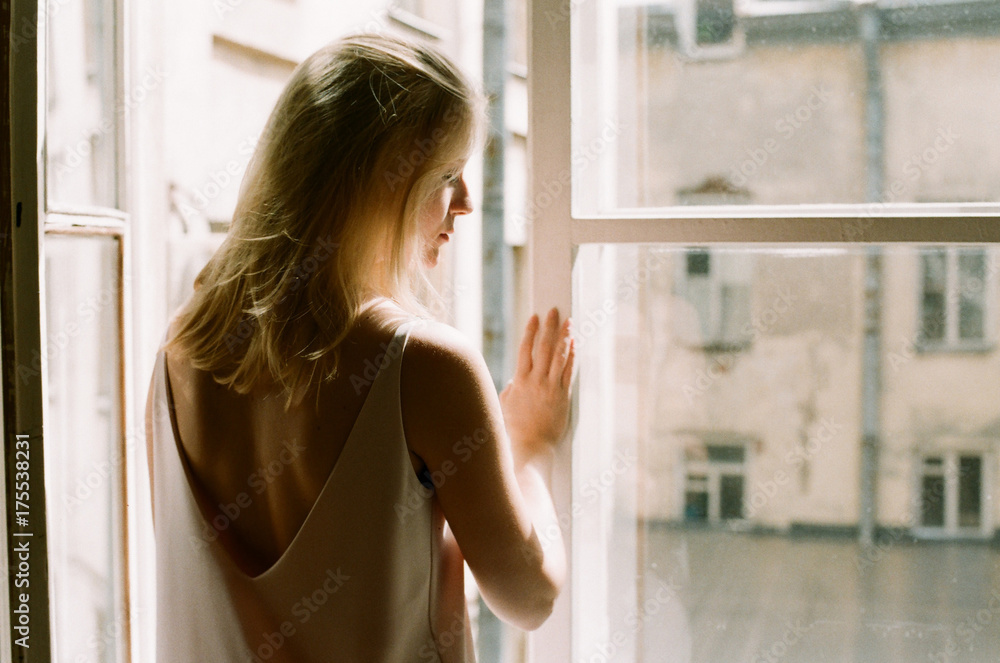Portrait of young woman standing against window Portrait of young woman standing against window