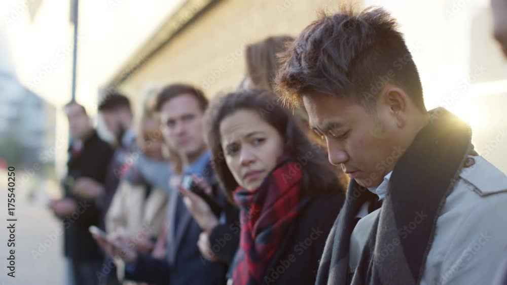 Diverse business group looking at smartphones while waiting in line Diverse business group looking at smartphones while waiting in line