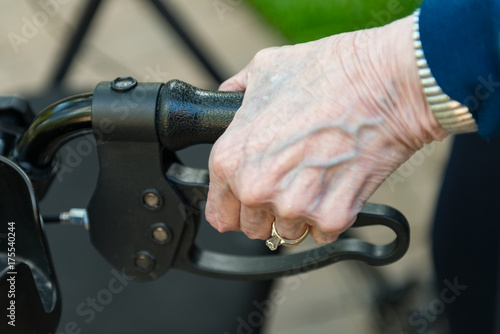 Elderly woman's hand gripping a walker with a shallow depth of field