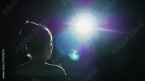 Girl in long gown performing on stage. the girl singing on the stage in front of the spotlight. Silhouette of singer standing on stage at microphone in night club