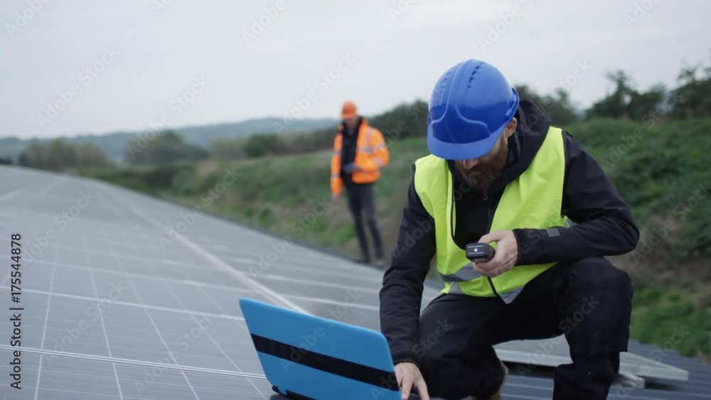Technician with laptop checking the panels at solar energy installation Technician with laptop checking the panels at solar energy installation