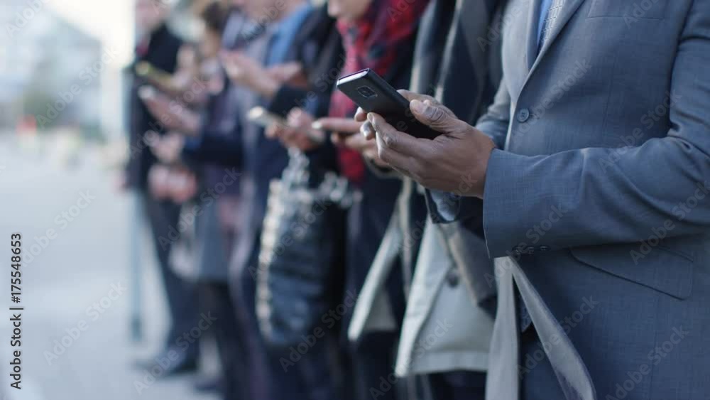  Diverse business group looking at smartphones while waiting in line