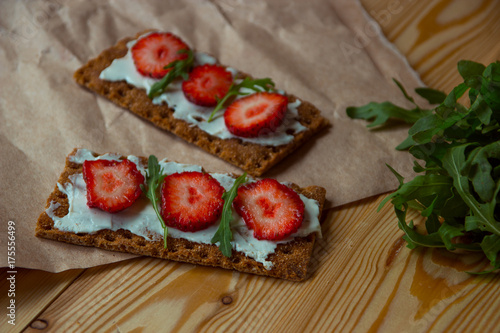 Wholegrain rye crispbread crackers with cream cheese, strawberry and arugula