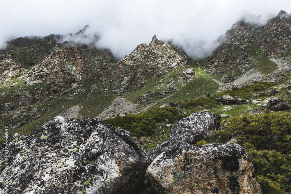 Mountain landscape with rocks and creeping fog. High peaks in the clouds, cold weather. Tourism in the mountains Mountain landscape with rocks and creeping fog. High peaks in the clouds, cold weather. Tourism in the mountains