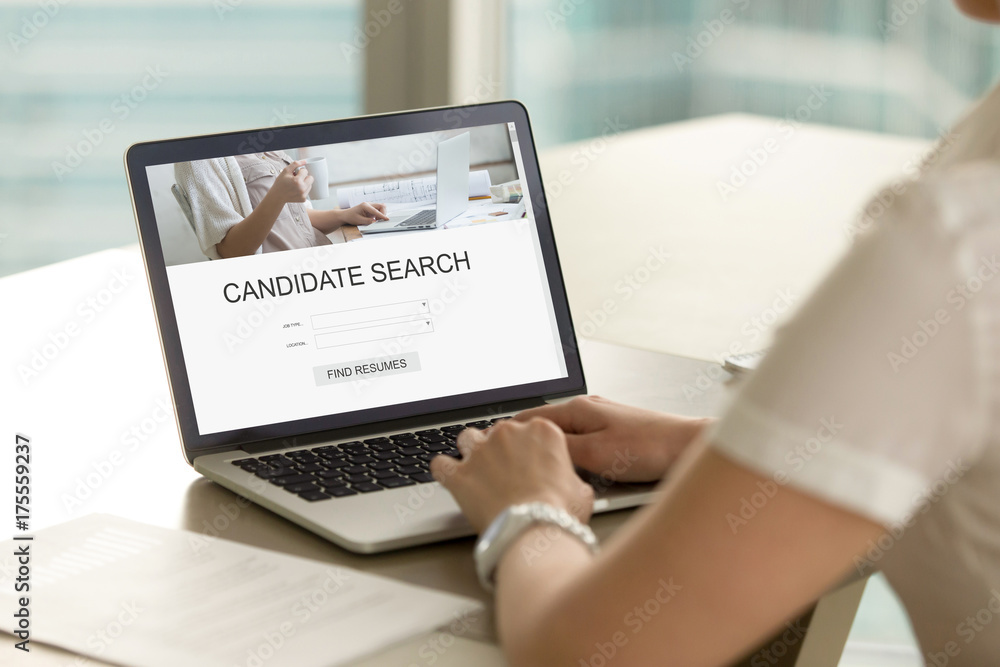 Casual businesswoman searching for job candidate using search engine on laptop. Employer searches for new professional staff. Headhunter browsing resumes. Close up view over shoulder, focus on screen. Casual businesswoman searching for job candidate using search engine on laptop. Employer searches for new professional staff. Headhunter browsing resumes. Close up view over shoulder, focus on screen.