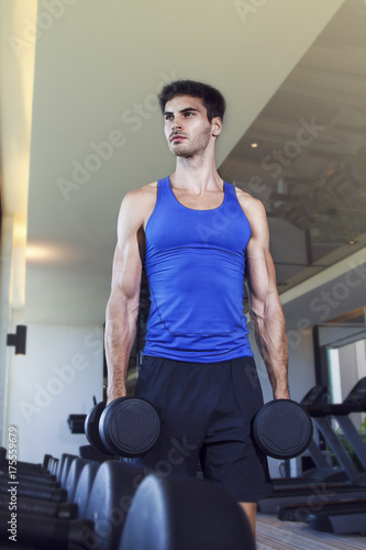 Young handsome muscular man exercising in the gym. Getting ready for first set.