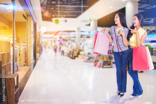 woman friends holding shopping bags money in hand excited to shopping in the shopping mall