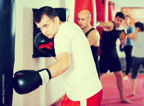 sportsman in the boxing hall practicing boxing punches with boxing bag