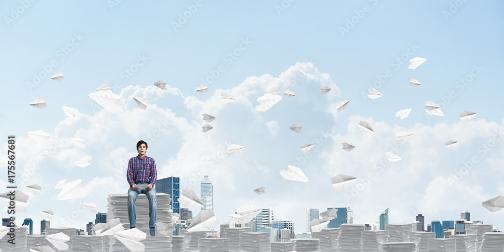Attractive man sitting on pile of paper documents. Attractive man sitting on pile of paper documents.