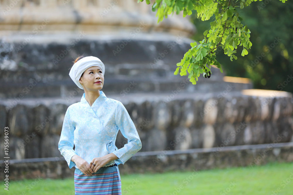 Fototapeta premium Thai woman wearing traditional Thai dress with old temple background