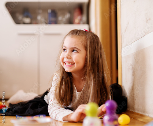 Pretty smiling toddler girl is playing with toys.