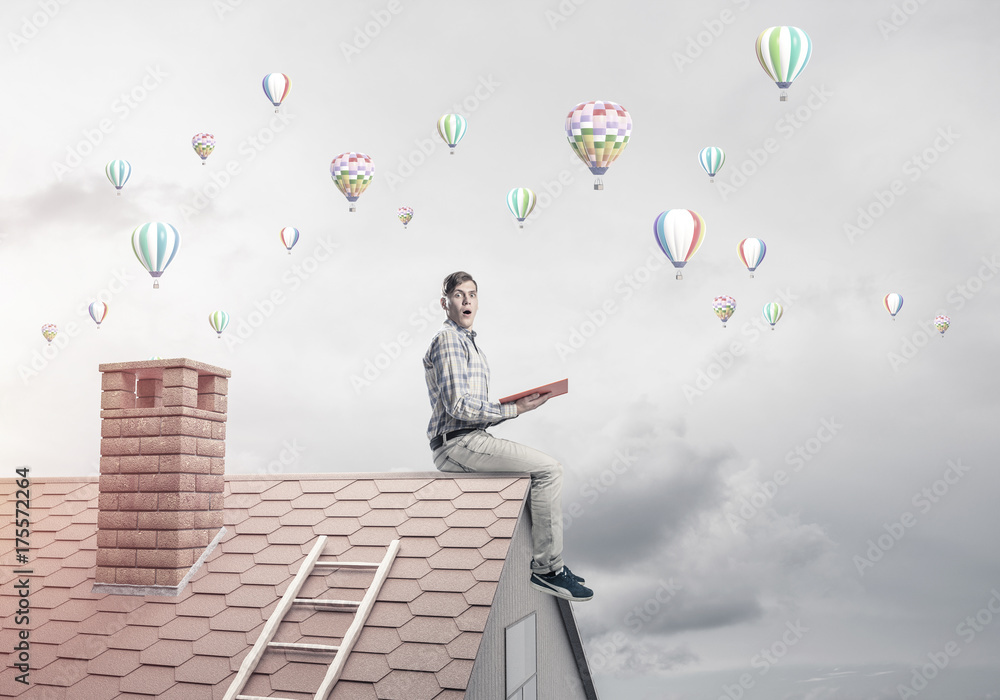 Handsome student guy reading book and aerostats flying in air Handsome student guy reading book and aerostats flying in air