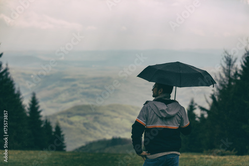 Hiker man holding umbrella in nature.