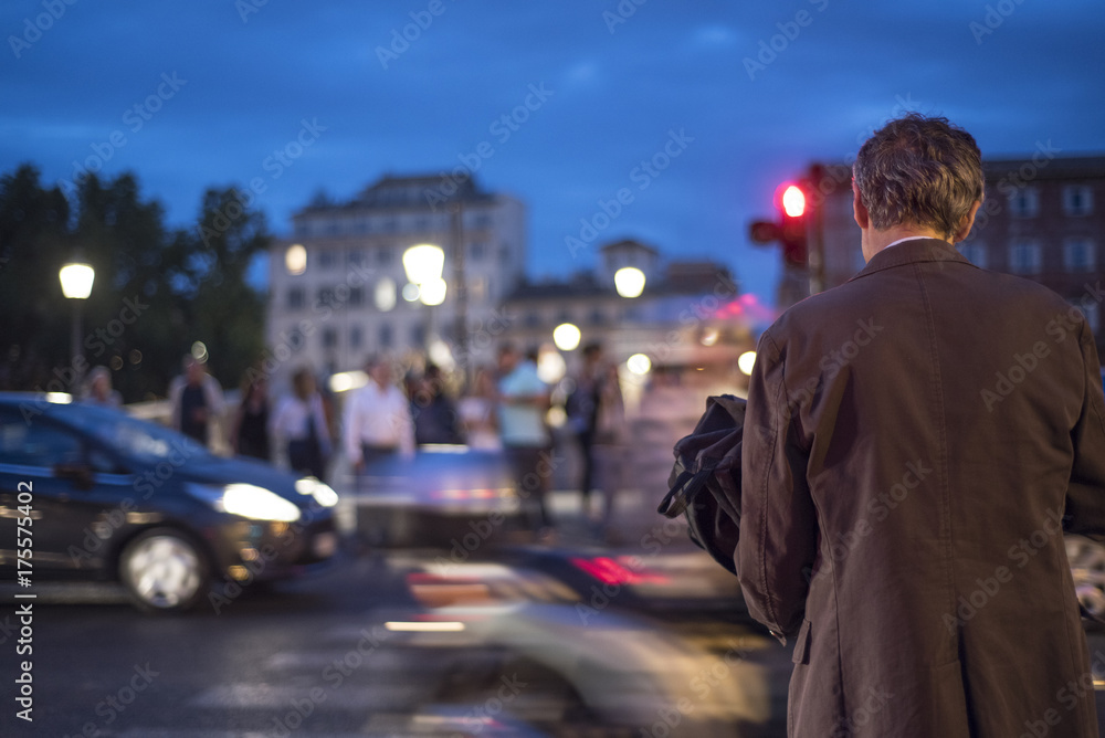 uomo in giacca che attraversa la strada in notturna