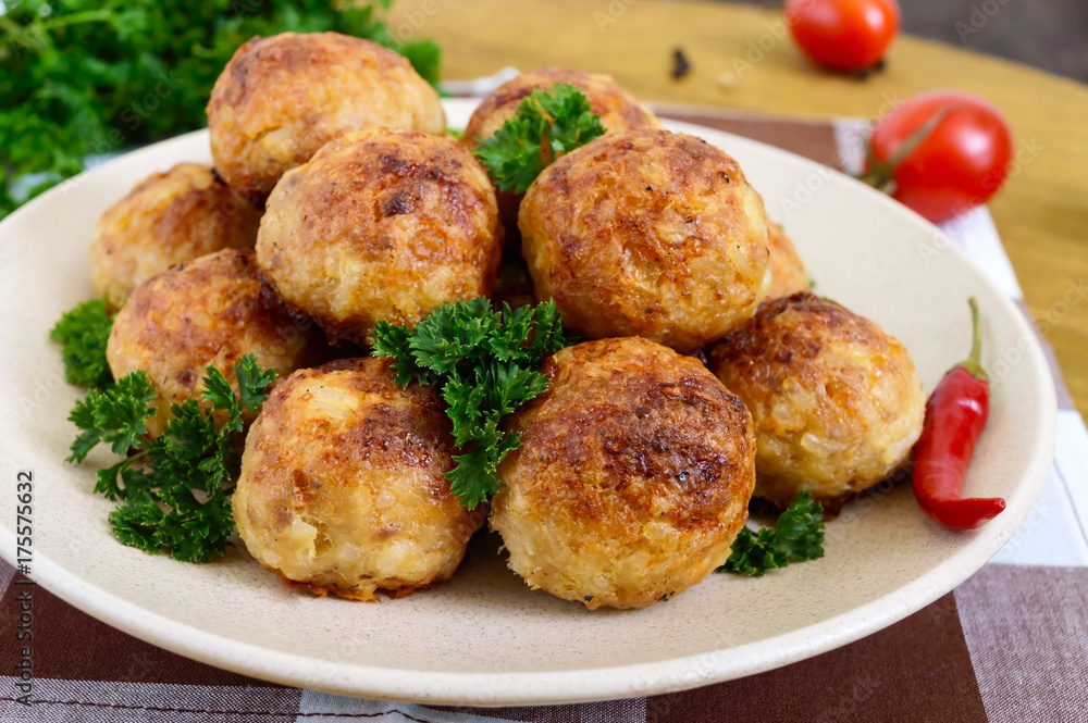 A pile of golden meat balls on a plate with parsley on a wooden table. Close-up A pile of golden meat balls on a plate with parsley on a wooden table. Close-up