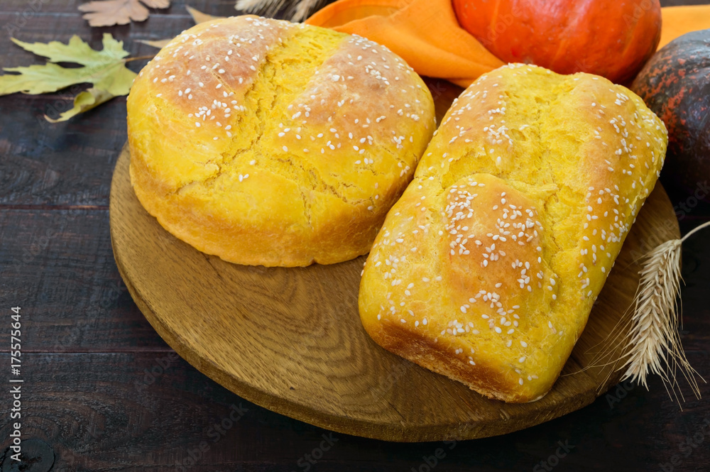 Golden homemade freshly baked pumpkin bread with sesame seeds on a dark wooden background. Golden homemade freshly baked pumpkin bread with sesame seeds on a dark wooden background.