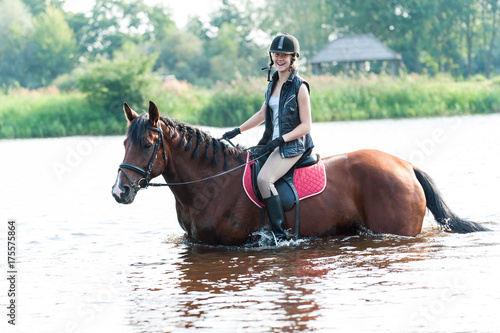Smiling young teenage girl riding horseback in river at early morning © AnnaElizabeth