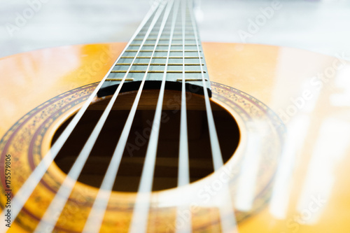 Classic acoustic guitar at weird and unusual perspective closeup. Six strings, free frets, sound hole and soundboard.