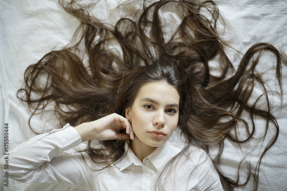 Fototapeta premium brunette with long hair outstretched on the bed