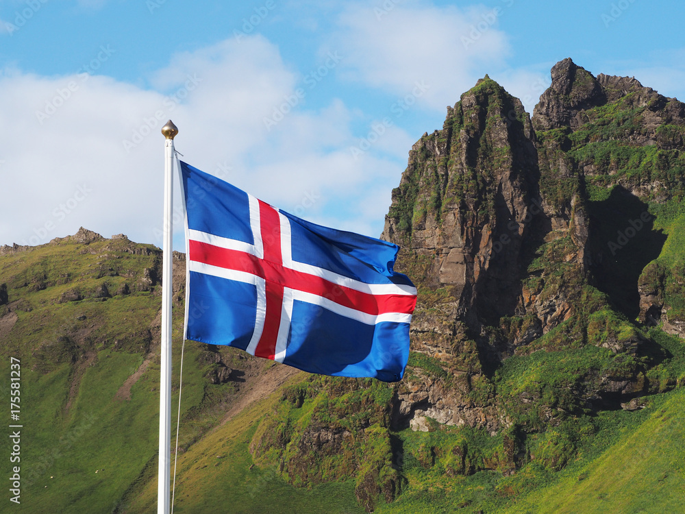 Obraz premium Flag of Iceland against the background of green mountains and blue sky