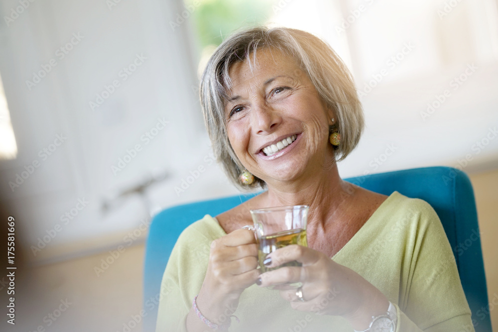 Senior woman relaxing in armchair drinking hot tea Senior woman relaxing in armchair drinking hot tea