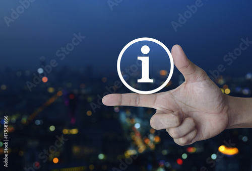 Information sign icon on finger over blur colorful night light city towerr, Business communication concept photo