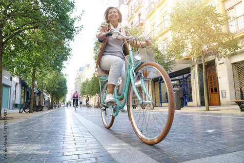 Starsza kobieta jedzie rower miejskiego w mieście