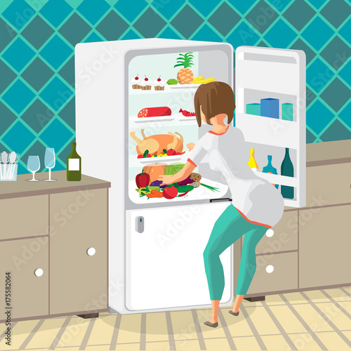 Young woman housewife takes out food from the refrigerator in th