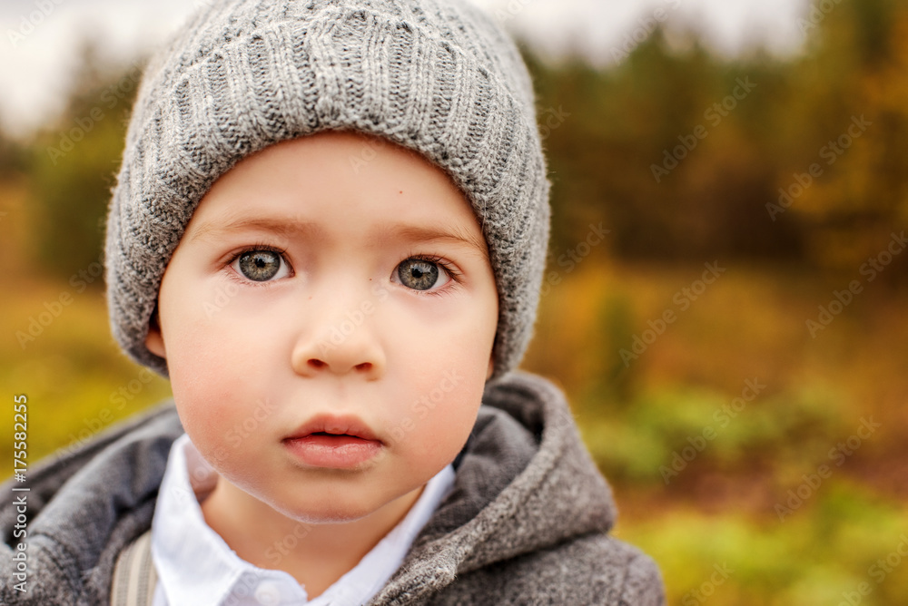 portrait of a cute little boy in a gray hat and jacket with huge beautiful eyes portrait of a cute little boy in a gray hat and jacket with huge beautiful eyes