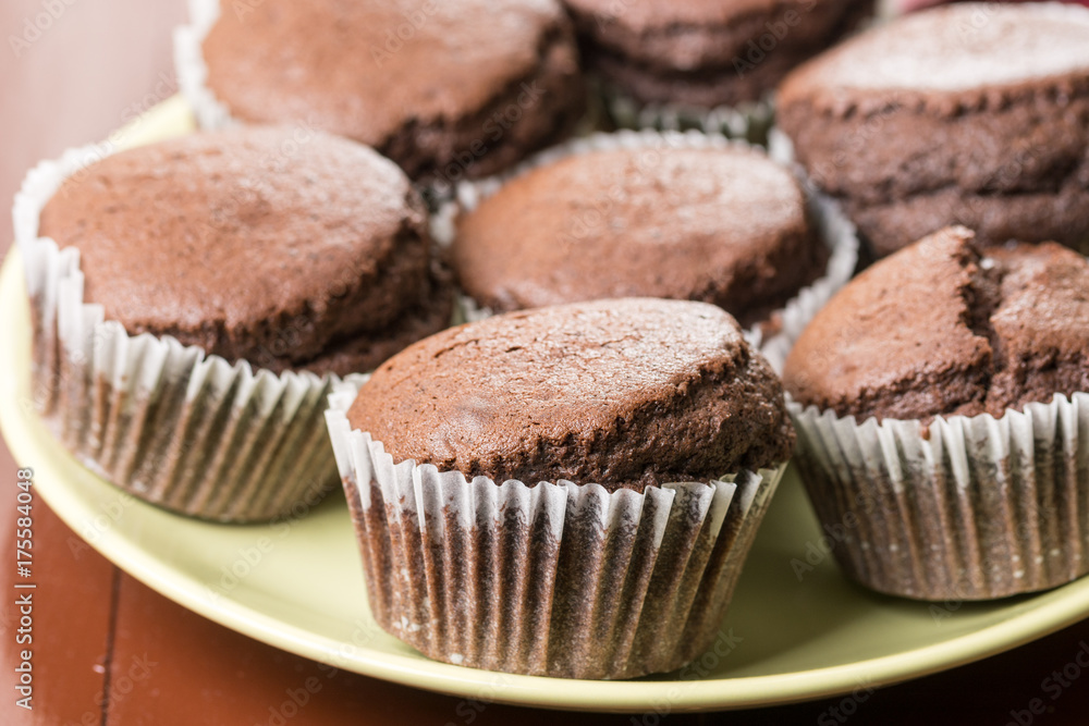 Fresh baked chocolate cup cakes served on the plate with kitchen dishtowel in the background Fresh baked chocolate cup cakes served on the plate with kitchen dishtowel in the background