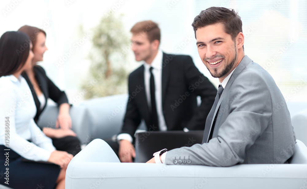 businessman sitting in an office on the background of business team. businessman sitting in an office on the background of business team.