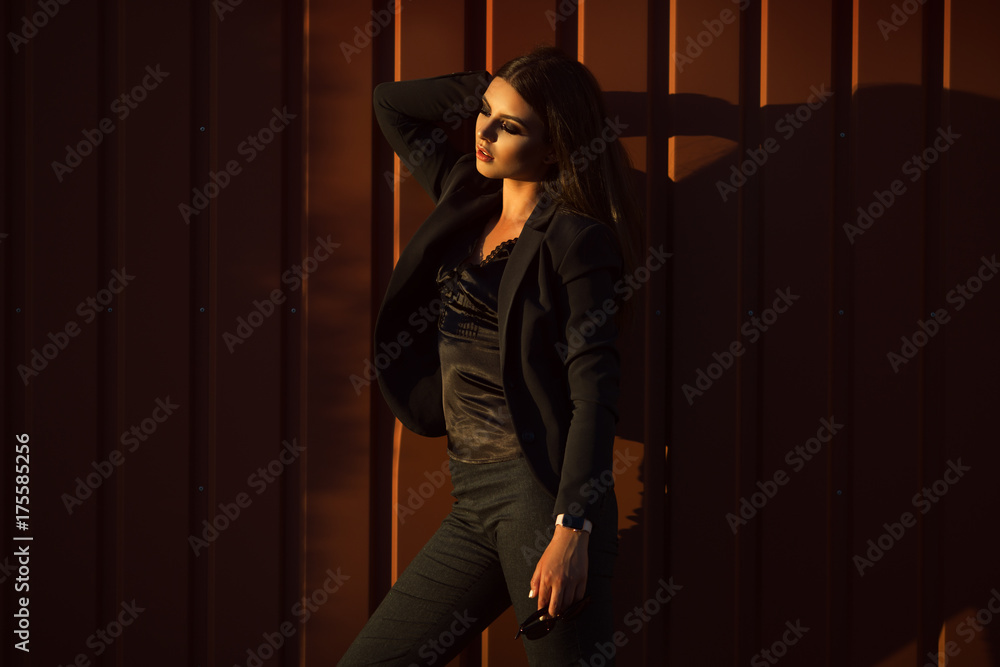 Portrait of pretty serious business woman is wearing black official clothes near wooden wall Portrait of pretty serious business woman is wearing black official clothes near wooden wall