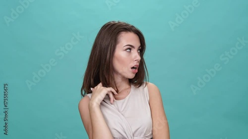 Pretentious brunette woman in t-shirt posing over turquoise background
