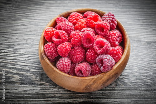 Bowl with ripe raspberries on wooden board