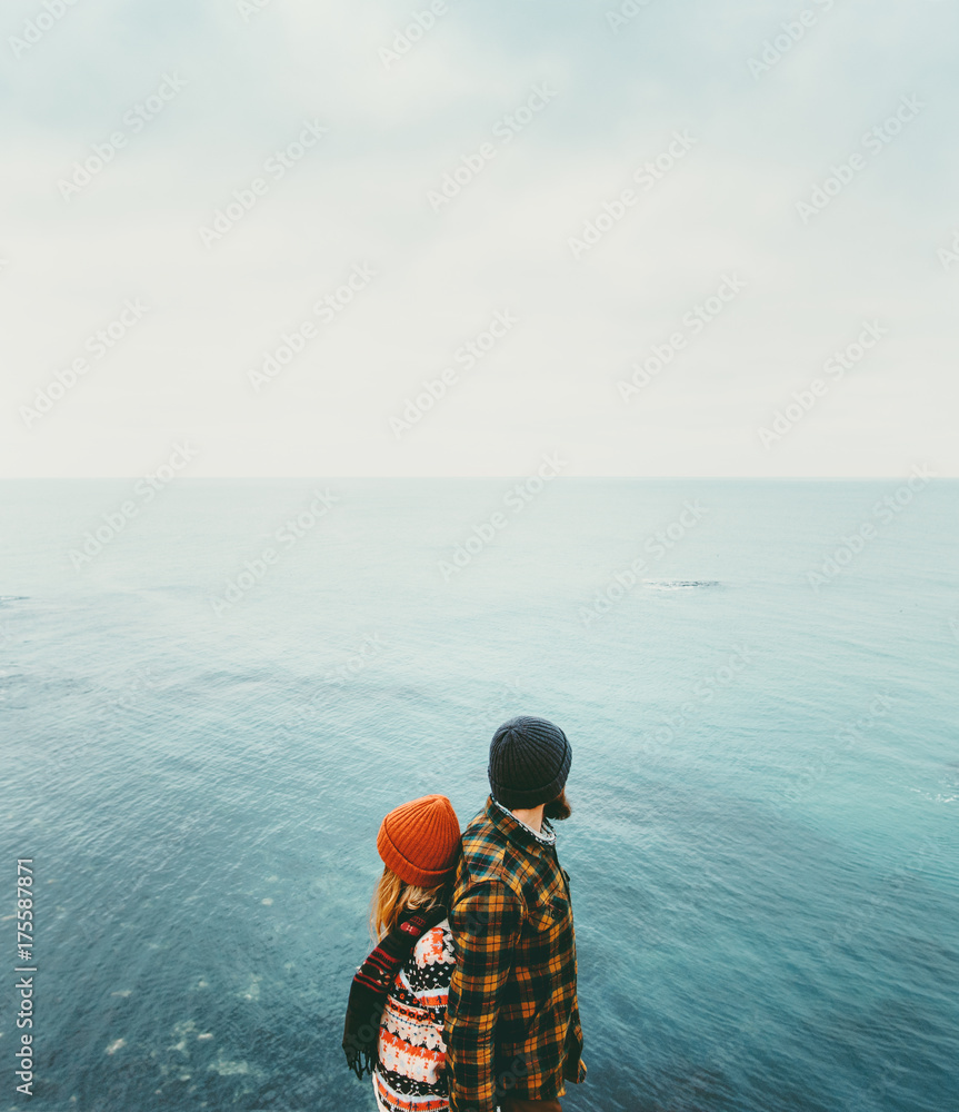 Fototapeta premium Couple in love Man and Woman back to back standing above sea Traveling together happy emotions Lifestyle concept. Young family romantic vacations journey